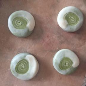 取半个卷卷，用手掌压扁，圈圈尽量集中在中间的部位。用擀面棍擀开，中间稍微厚一点，两边薄一点。尽量让圈圈集中在中心的位置。