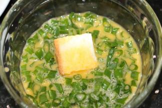 把吐司方迅速沾上鸡蛋液，沾些葱花