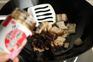 炒锅放油，五花肉和葱姜同炒，炒至五花肉变的透亮油润，加入香菇酱。