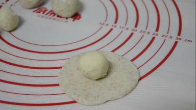 取一份水油皮擀成中间厚两边薄的饼皮，放上油酥，虎口上推慢慢收紧，捏紧收口