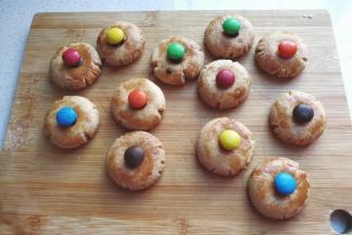 黑巧力装裱花袋隔热水融化，然后挤适量在饼干凹处，再摆上m豆沾紧；