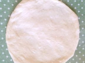 取出醒好的一个面团，排气、揉圆，用擀面杖将其擀平，直径约为16厘米上下。

面团擀好是会回缩的，千万不要着急，一边继续醒一边擀。