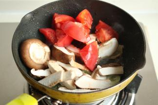 下入香菇片和西红柿翻炒。