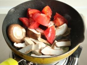 下入香菇片和西红柿翻炒。
