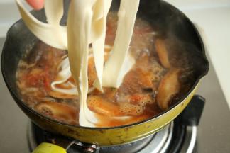 烩面胚子已经醒发好了，很容易就能拉成又薄又长的面片，下入锅里。