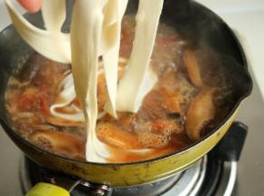 烩面胚子已经醒发好了，很容易就能拉成又薄又长的面片，下入锅里。