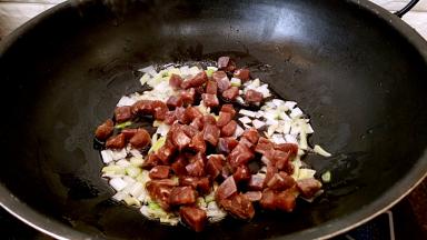 放入香肠丁小火煸炒变色。