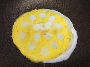 蛋黄蛋皮铺回不粘锅里，把蛋清用小勺填满小花空里，煎熟。我把蛋清全倒进去了，锅没有放平，歪了一边，不过不影响，一会儿边还要装饰，可以盖住白边。