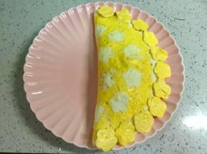 把蛋皮盖上炒饭，边缘压一压，再把之前压出的小花摆在边上。