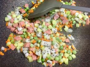 接着把不容易熟的胡萝卜丁和豌豆先炒一会儿，再放入其他蔬菜丁和火腿丁，翻炒。（第一次用火龙果炒饭，疏忽了，火龙果丁应该在炒完米饭后，最后再放，这样才不会炒碎了）