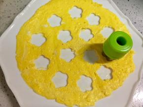 把煎蛋黄皮取出，铺在平盘里，用小花模具按出小花的空，压出的小花蛋皮放一边备用。我怕模具把不粘锅涂层划坏，所以拿出锅压的。