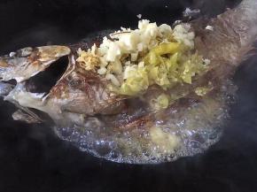 鱼煎至两面金黄，将大蒜，生姜，泡椒切碎，放入