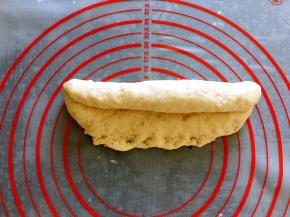 松弛后的面团擀成椭圆形，翻面后压薄长底边，自上而下卷成条状，并慢慢搓至需要的长度。