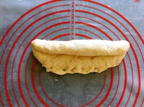 松弛后的面团擀成椭圆形，翻面后压薄长底边，自上而下卷成条状，并慢慢搓至需要的长度。