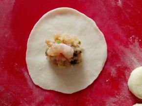 先把面剂子按成圆饼，再用擀面杖擀成圆盘，中间包好饺子馅，