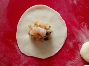 先把面剂子按成圆饼，再用擀面杖擀成圆盘，中间包好饺子馅，