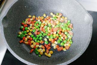 锅中入少许油，下入玉米粒、青豆和火腿丁翻炒一下；