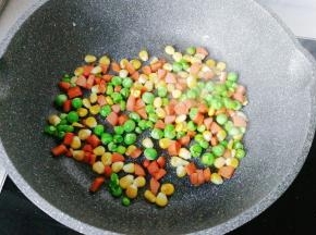 锅中入少许油，下入玉米粒、青豆和火腿丁翻炒一下；