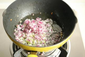 接下来开始做咖喱鱼丸。平底锅放色拉油，下入洋葱末和葱末爆出香味。