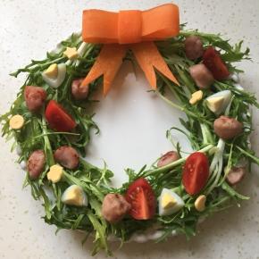 把香肠、鹌鹑蛋、小番茄和芝士放苦菊上装饰，并按上胡萝卜蝴蝶结