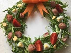 把香肠、鹌鹑蛋、小番茄和芝士放苦菊上装饰，并按上胡萝卜蝴蝶结