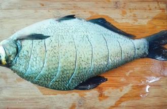 鳊鱼刮去鱼鳞，去掉内脏，鱼鳃洗干净，用刀在表面划切数刀