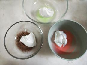 将蛋白霜分别挖一小勺加入装有不同果味粉的碗中，翻拌均匀。