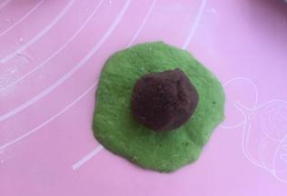 取绿色面团擀开，抱紧豆沙馅