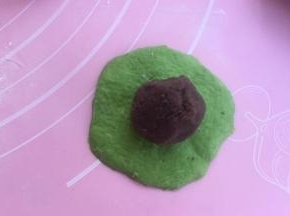 取绿色面团擀开，抱紧豆沙馅