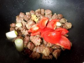 放入番茄、大葱、蒜瓣、生姜、八角翻炒均匀。