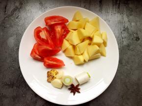 将番茄去皮切块，土豆切滚刀块，葱切段，蒜拍烂。