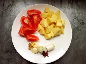 将番茄去皮切块，土豆切滚刀块，葱切段，蒜拍烂。