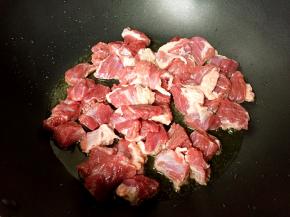 放入牛腩煸干水分。