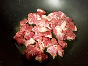 放入牛腩煸干水分。