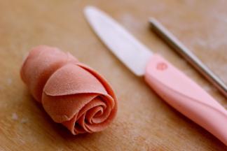 然后把面皮翻过来、从底部向上卷起、一直卷到头、用刀从中间切开就是两朵玫瑰花