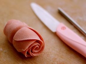 然后把面皮翻过来、从底部向上卷起、一直卷到头、用刀从中间切开就是两朵玫瑰花