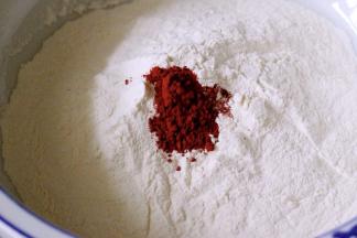 面粉中加入红曲粉混合均匀后、酵母用少许温水化开、慢慢倒入面粉中搅拌