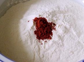 面粉中加入红曲粉混合均匀后、酵母用少许温水化开、慢慢倒入面粉中搅拌