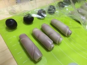 从牛舌状面团的一头卷起，盖上保鲜膜松弛15分钟