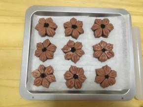 全部整好桃花的形状以后，在中间抹上全蛋液，撒上熟黑芝麻