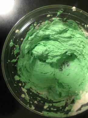 取一大勺淡奶油拌上绿色色素，在蛋糕底部挤上一圈绿圆珠做装饰，剩下的换个裱花嘴，挤在顶上做小草装饰