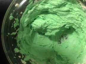 取一大勺淡奶油拌上绿色色素，在蛋糕底部挤上一圈绿圆珠做装饰，剩下的换个裱花嘴，挤在顶上做小草装饰