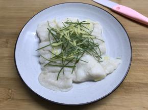 8分钟后把蒸好的龙利鱼取出，倒去水后放上葱、姜丝。