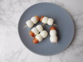 每两个鹌鹑蛋组合在一起，上面用烤肉肠段当帽子，用牙签固定。