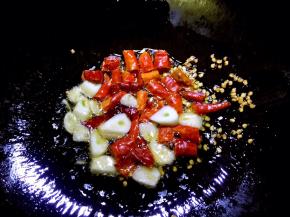 锅内放油烧至六成热，放入辣椒段和蒜片爆香