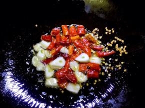 锅内放油烧至六成热，放入辣椒段和蒜片爆香