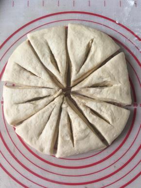 5张面片重叠之后，用擀面杖擀擀，把面片里的空气擀出让其更贴服。 面包坯子用刀平均分为8等分，在每份中间割开一口子（如图），不要割断。