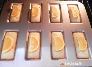 烤7分钟后，将橙子片分别码在：每个“金砖”的中间。该模具导热性很好， 再烤7分钟左右表面金黄即可。