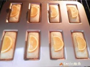 烤7分钟后，将橙子片分别码在：每个“金砖”的中间。该模具导热性很好， 再烤7分钟左右表面金黄即可。