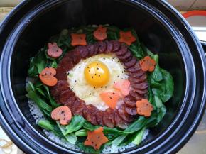 快速把青菜、腊肠、胡萝卜摆成自己喜欢的造型，打入一个鸡蛋，洒上一点黑芝麻，从边缘倒入少量油，盖上锅盖，用最小火煮三分钟，然后关火继续焖15分钟。